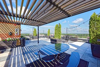 An outdoor patio with a blue table and chairs and a view of the city